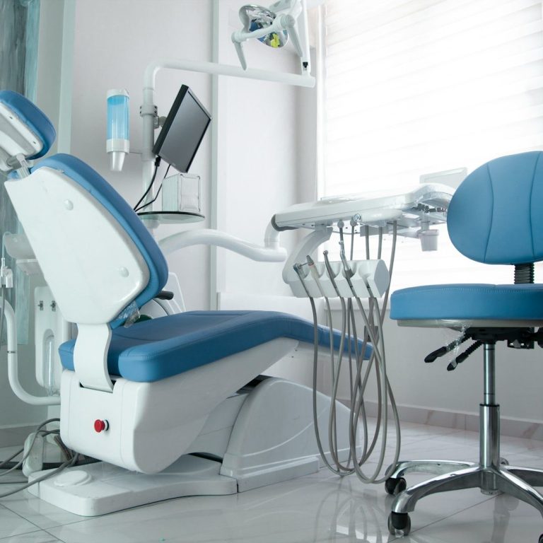 Cabinet dentaire avec un fauteuil, un équipement médical et une chaise d'invité.