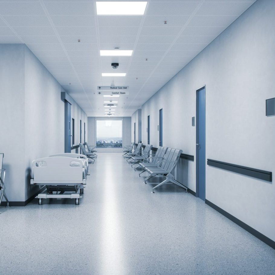 Couloir lumineux d'hôpital avec chariots et chaises alignées sur les côtés.