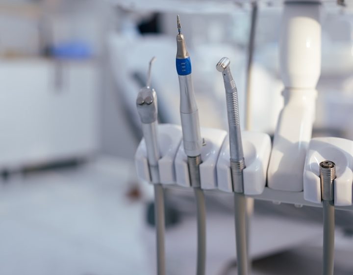 Des outils dentaires alignés sur un support dans un cabinet dentaire.