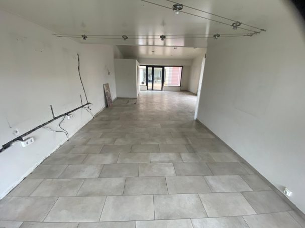 Remise en état après travaux commerce Intérieur d'un espace vide avec un sol carrelé et des murs blancs.