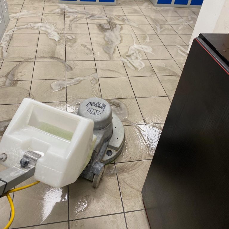 Une personne passe l'aspirateur sur un matelas gris.