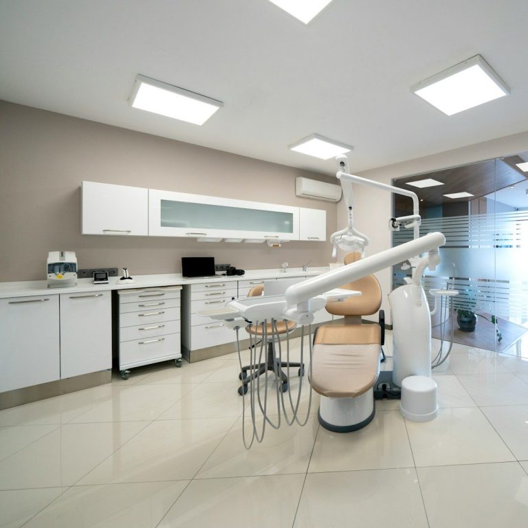 Cabinet dentaire moderne avec chaise, équipements et lumière naturelle.